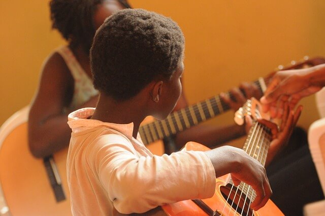 criança aprendendo a tocar violão